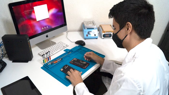 Profissional da Fixnow trabalhando em um celular na bancada da loja